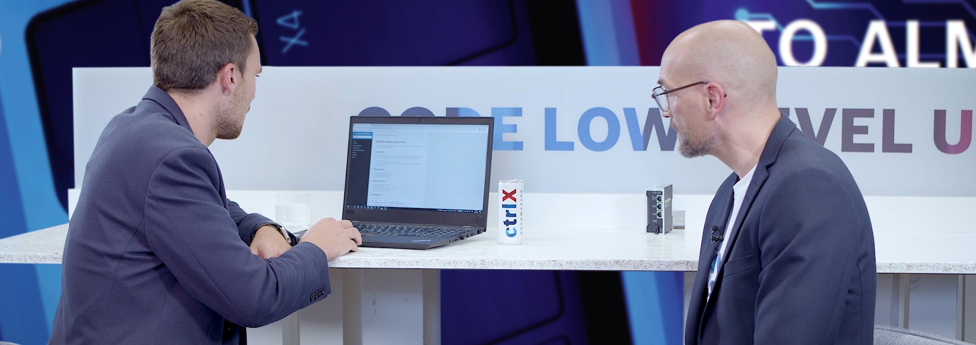 Gospodarz Christian Zentraf i jego gość Johannes Albrecht siedzą przy stole i rozmawiają o Software Development Kit (SDK) do tworzenia aplikacji dla rozwiązania automatyzacji ctrlX AUTOMATION.