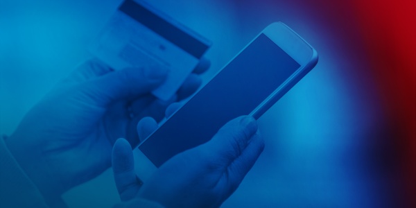 Smartfon i karta bankowa są trzymane w jednej ręce.