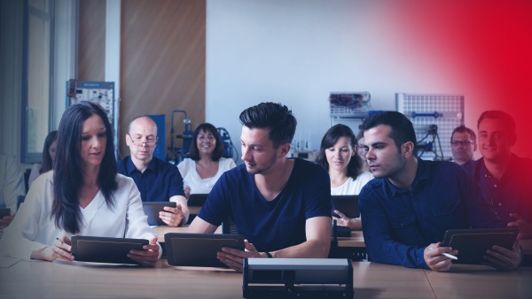 Teilnehmende eines Face-to-Face-Trainings sitzen in einem Schulungsraum. Sie nutzen Tablets zur Wissensvermittlung.