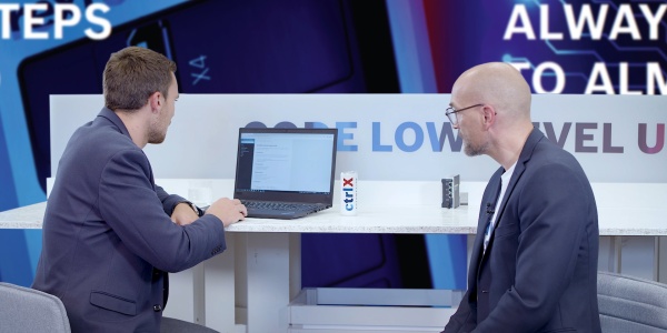 Gospodarz Christian Zentraf i jego gość Johannes Albrecht siedzą przy stole i rozmawiają o Software Development Kit (SDK) do tworzenia aplikacji dla rozwiązania automatyzacji ctrlX AUTOMATION.