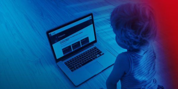Małe dziecko klęczy przed laptopem i patrzy na ctrlX Configurator