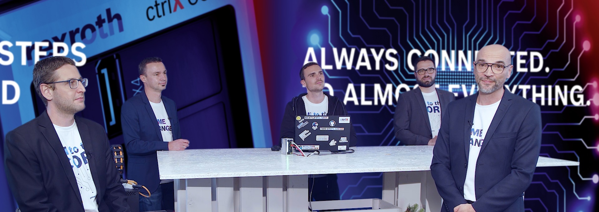 Gospodarz Christian Zentraf i jego goście Johannes Albrecht, Pedro Reboredo, Holger Schnabel i Kai Müller siedzą przy stole i rozmawiają o graficznym programowaniu za pomocą Blockly rozwiązania automatyzacji ctrlX AUTOMATION