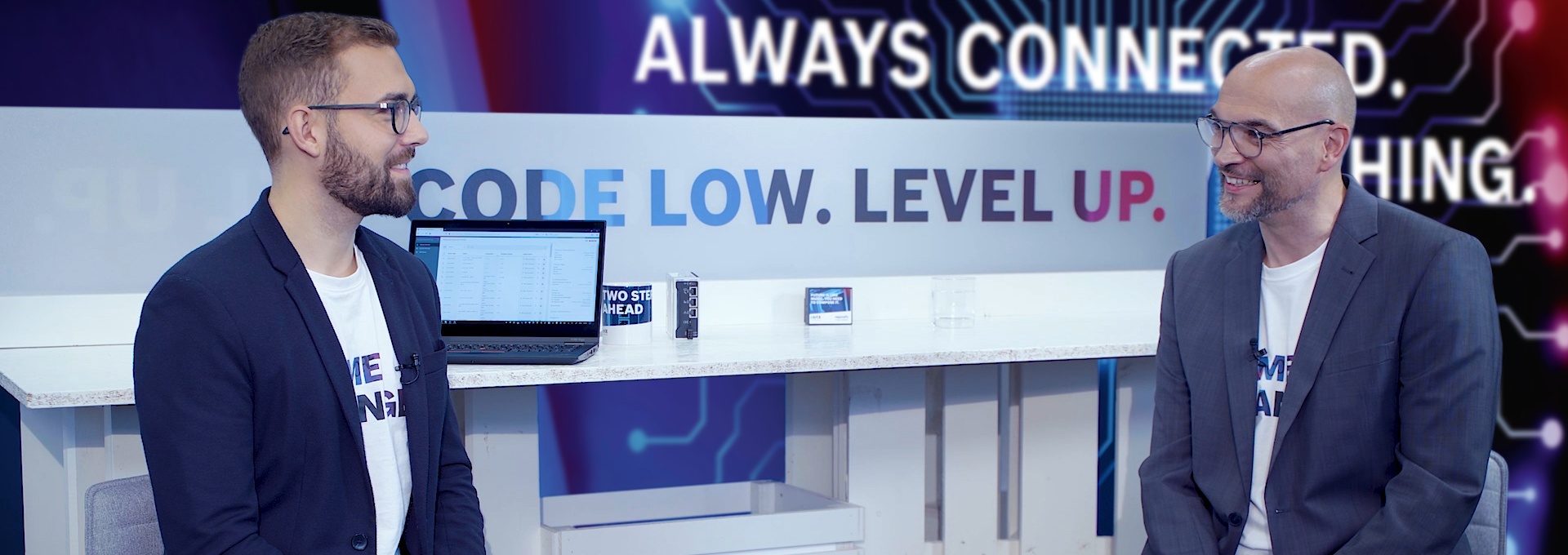 Gospodarz Christian Zentraf i jego gość Julian Weinkoetz siedzą przy stole i rozmawiają o ctrlX Device Portal, centralnym menedżerze urządzeń w rozwiązaniu automatyzacji ctrlX AUTOMATION.