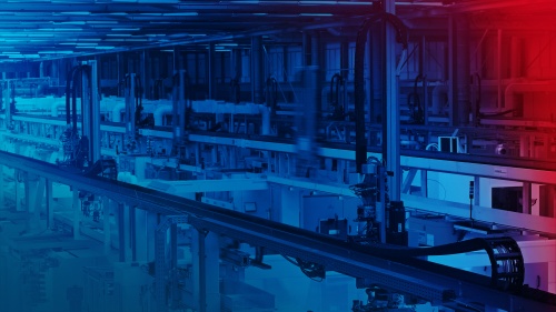 Hala fabryczna z robotami bramowymi, które zaopatrują centra obróbcze w materiał