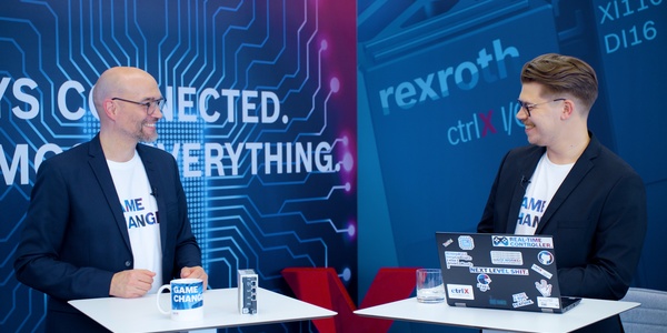 Gospodarz Christian Zentraf i jego gość Benedikt Rüb stoją przy stołach i rozmawiają o ctrlX Configurator, narzędziu konfiguracyjnym rozwiązania automatyzacji ctrlX AUTOMATION.