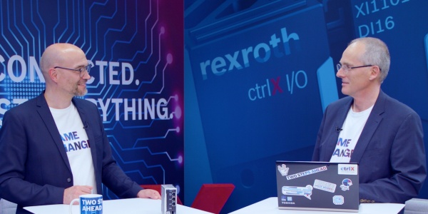 Gospodarz Christian Zentraf i jego gość Thomas Fey stoją przy stołach konferencyjnych i rozmawiają o internetowych aplikacjach HMI do obsługi i wizualizacji, o rozwiązaniu automatyzacji ctrlX AUTOMATION.